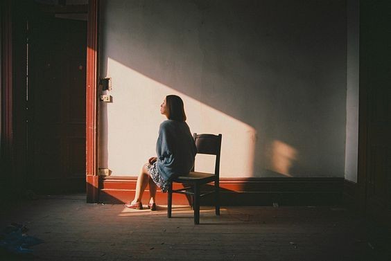 Mujer sentada a solas en una silla mirando la ventana