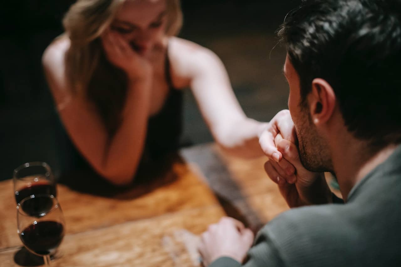 Hombre besando la mano a una mujer en una cita