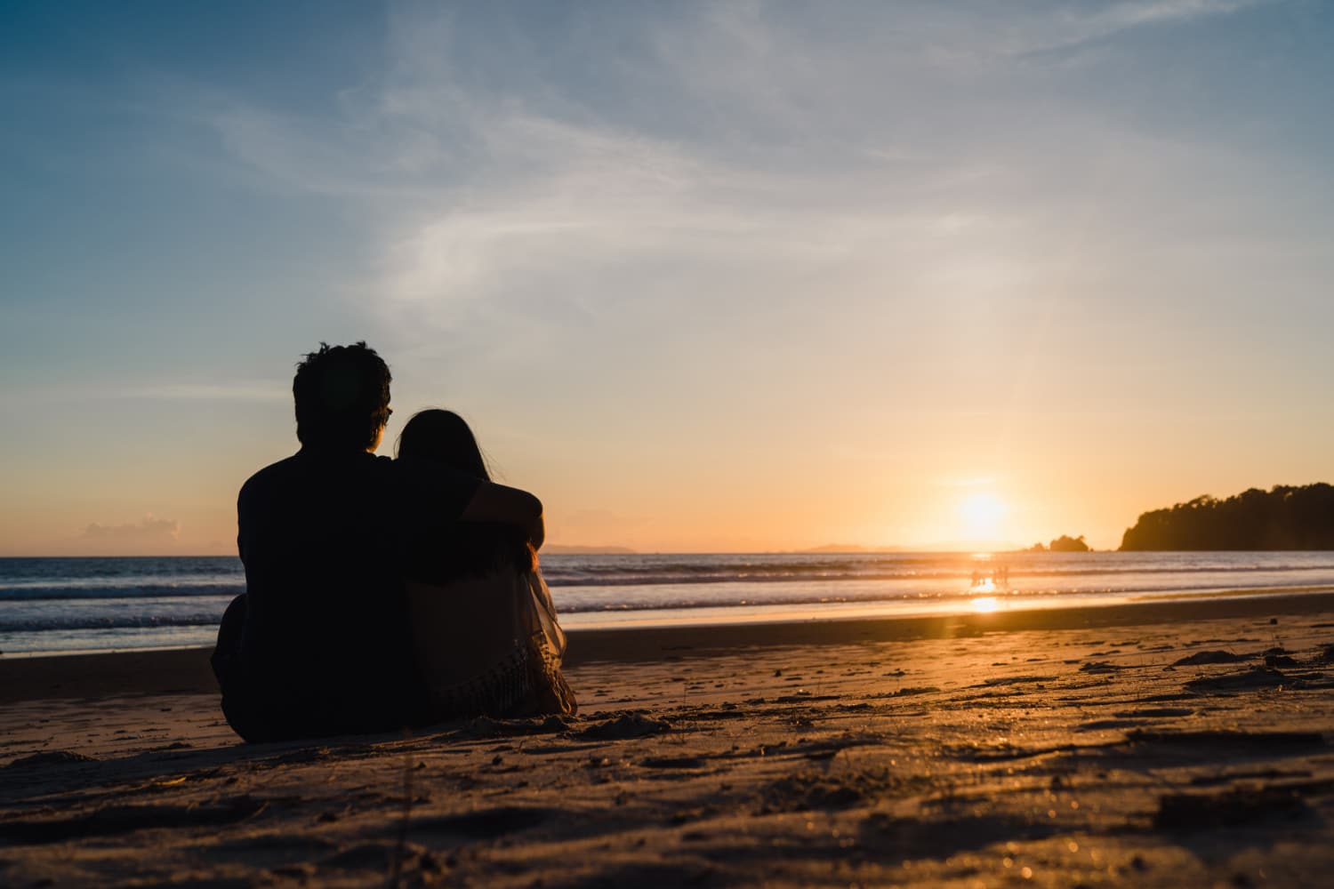 Pareja viendo puesta de sol cerca de la playa en momento romántico
