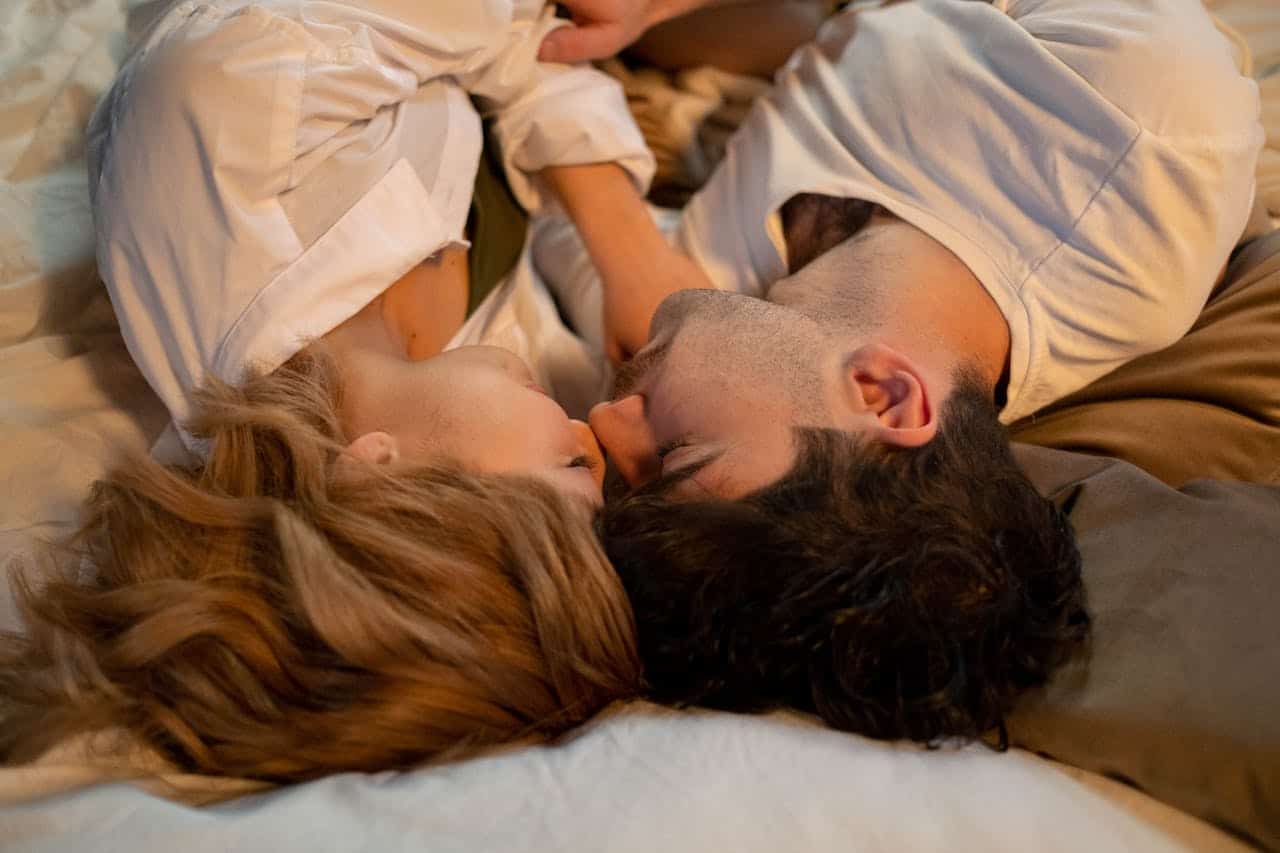 pareja cama durmiendo beso